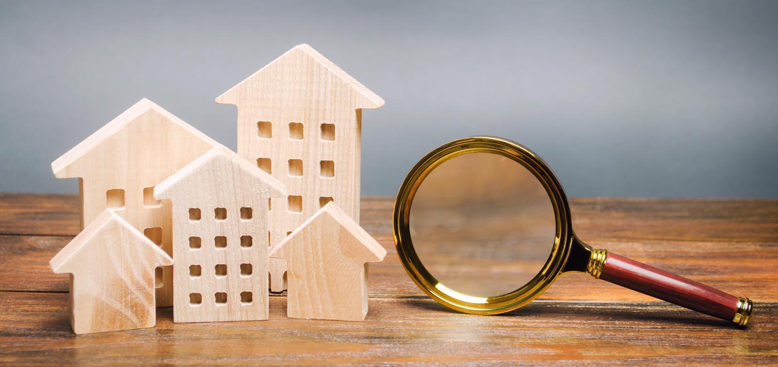 Afbeelding van een vergrootglas naast houten huisjes